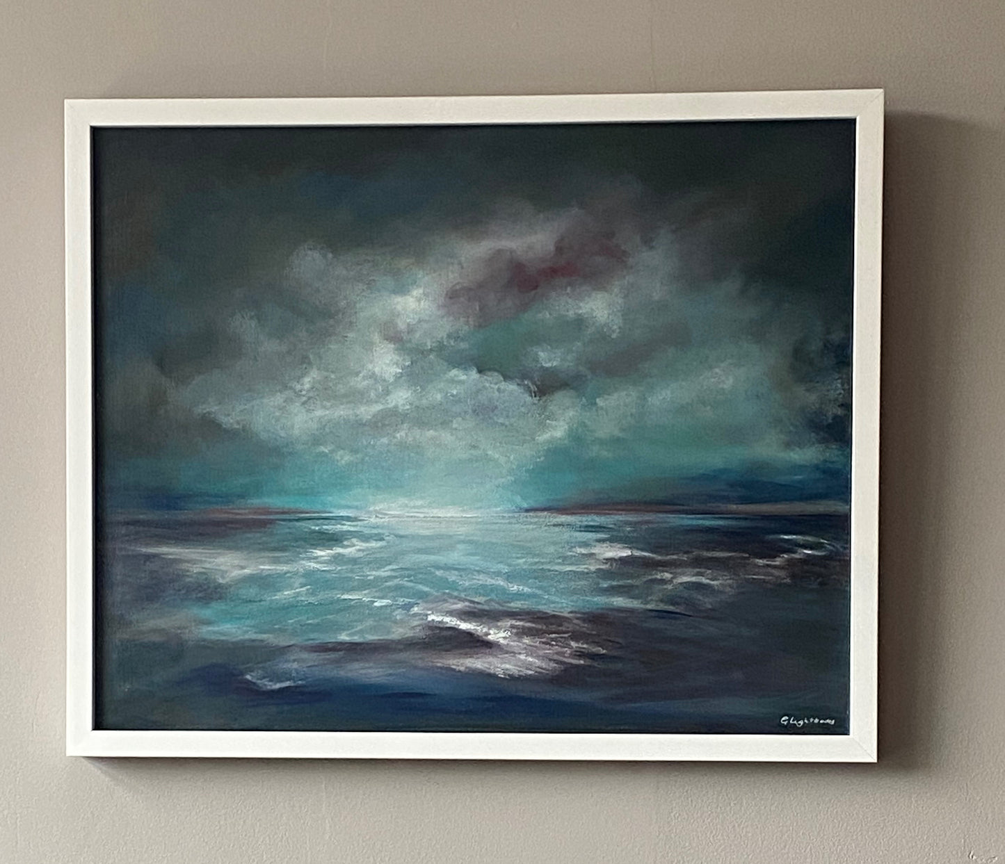Framed painting of a stormy sea with dark clouds on a beige wall