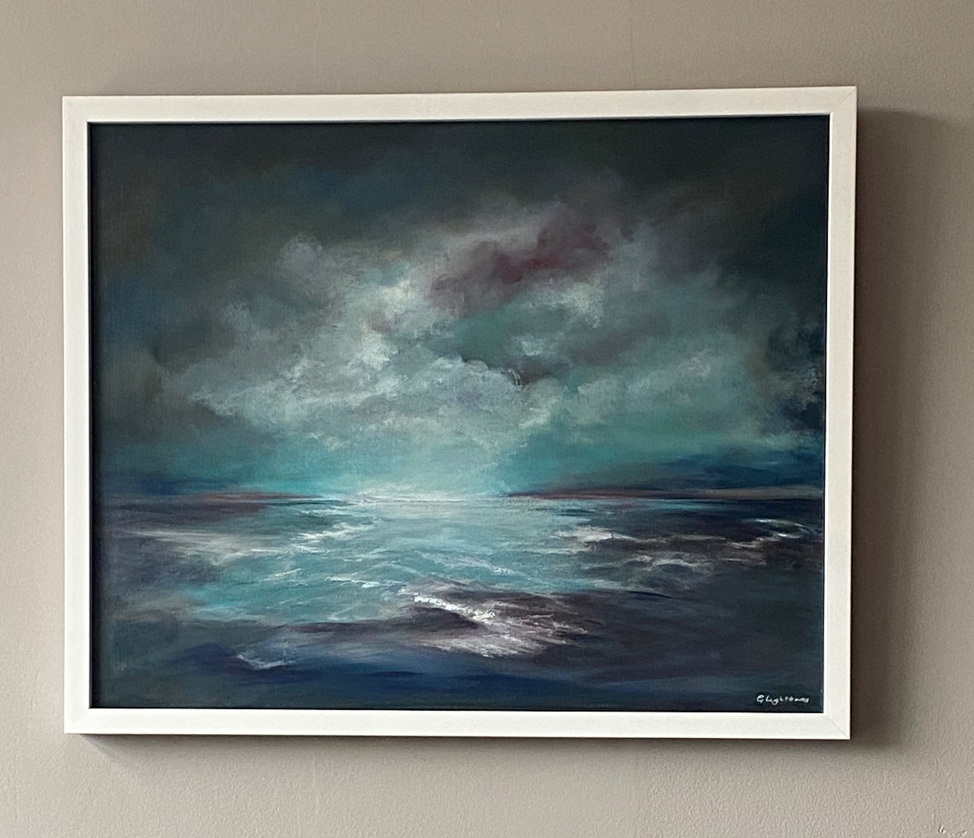 Framed painting of a stormy sea with dark clouds on a beige wall