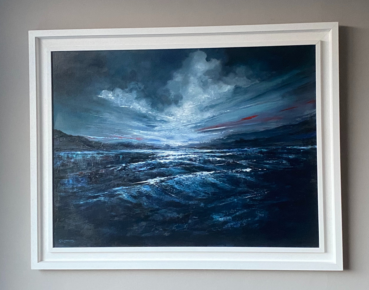 Framed painting of a stormy landscape with dark blue sky and water.