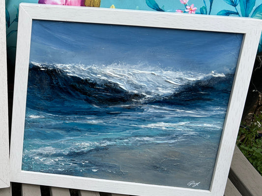 A framed painting of ocean waves on canvas