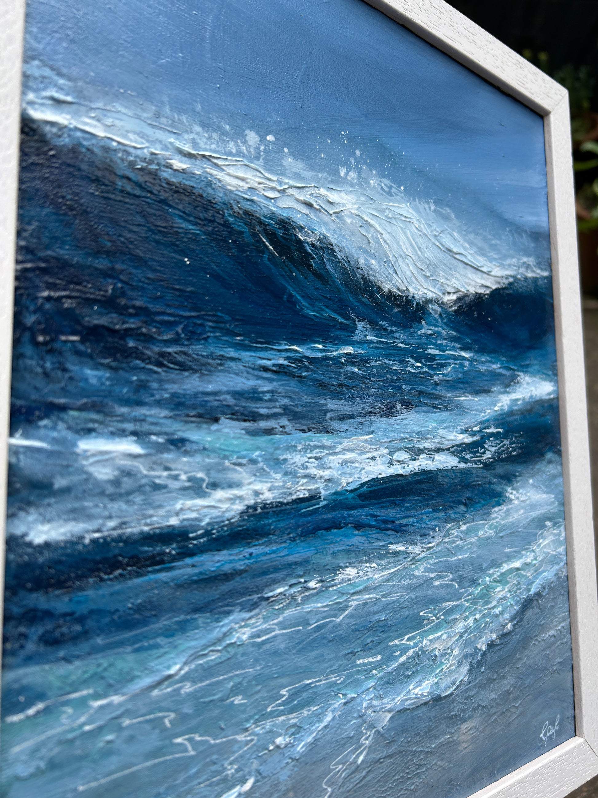 Framed artwork of a dynamic ocean wave with a white frame.
