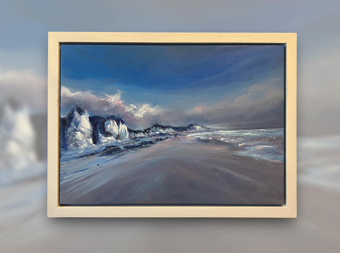 Framed artwork of a beach scene with waves and rocks on a wall.